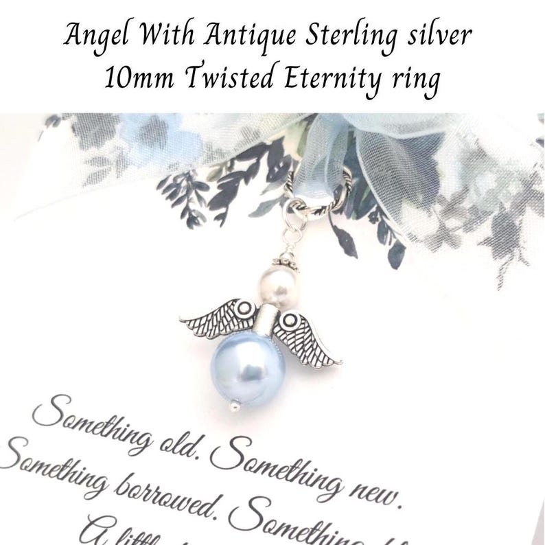 May include: A silver angel charm with a light blue pearl body and pearl head, detailed wings, and a silver loop. The charm is attached to a light blue ribbon with floral accents. Text reads "Something old. Something new."