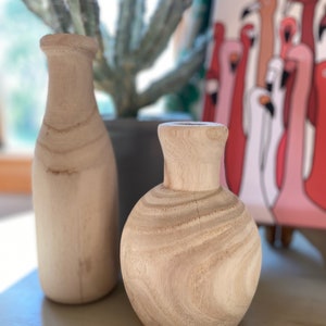 May include: Two wooden vases, one tall and narrow, the other short and round, both with a natural wood finish.