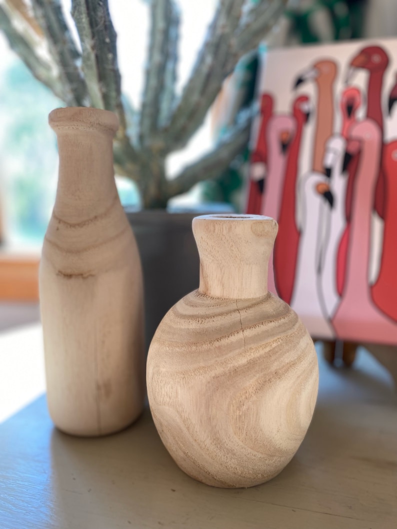May include: Two wooden vases, one tall and narrow, the other short and round, both with a natural wood finish.