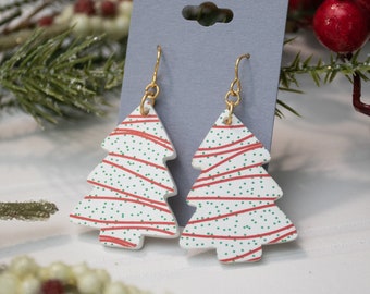 Puede incluir: Un par de pendientes de árbol de Navidad blancos con rayas rojas y verdes y lunares verdes. Los pendientes están hechos de arcilla polimérica y tienen ganchos dorados.