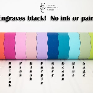 May include: A close-up of a roll of wood showing different colors of wood. The colors are red, coral, hot pink, pink, blush, purple, navy, ocean, blue, sage, lime, and yellow. The text "Engraves black! No ink or paint!" is above the roll of wood.