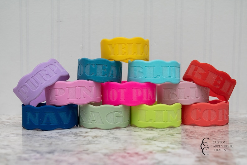 Puede incluir: Una pila de pulseras de silicona de colores con diferentes palabras en relieve, incluyendo "PURP", "PINK", "OCEAN", "YELLOW", "BLUE", "RED", "NAVY", "SAGE", "LIME" y "CORAL".
