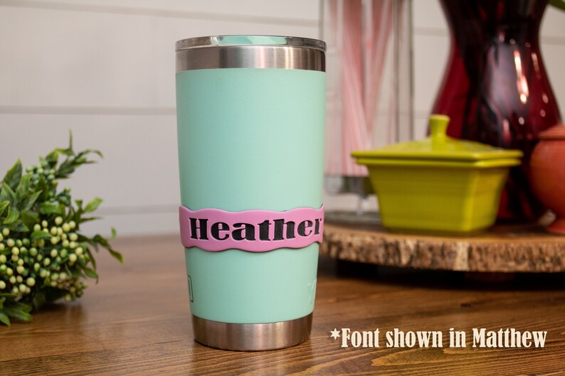 May include: A light green stainless steel tumbler with a pink personalized name band that says "Heather".
