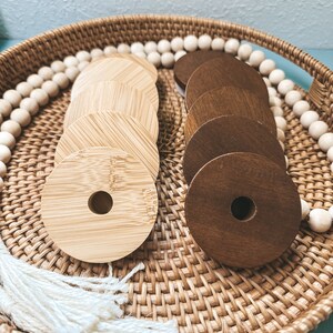 May include: A wicker basket filled with wooden rings, some are light brown and some are dark brown. The basket is lined with white beads.