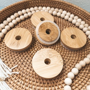 May include: Four round wooden lids with a hole in the center, sitting on a woven basket with white beads around the edge.