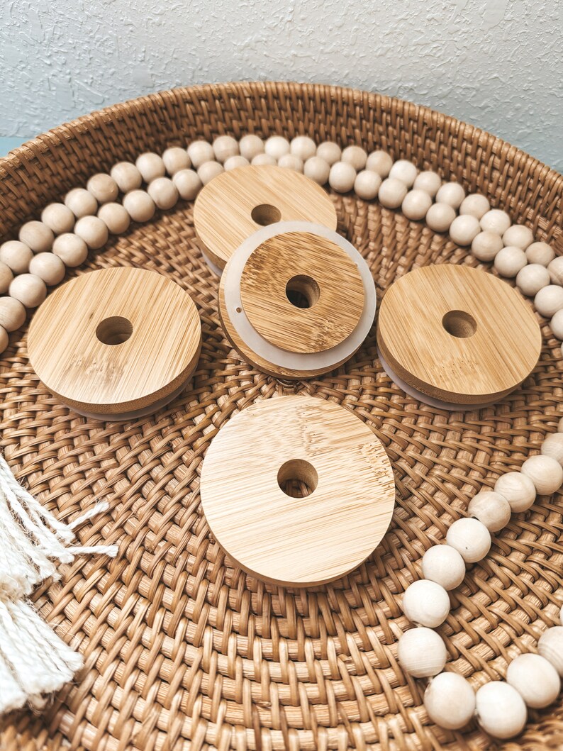 May include: Four round wooden lids with a hole in the center, sitting on a woven basket with white beads around the edge.