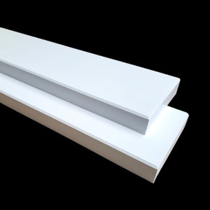 May include: Two white wooden shelves, one on top of the other, with a slightly beveled edge.