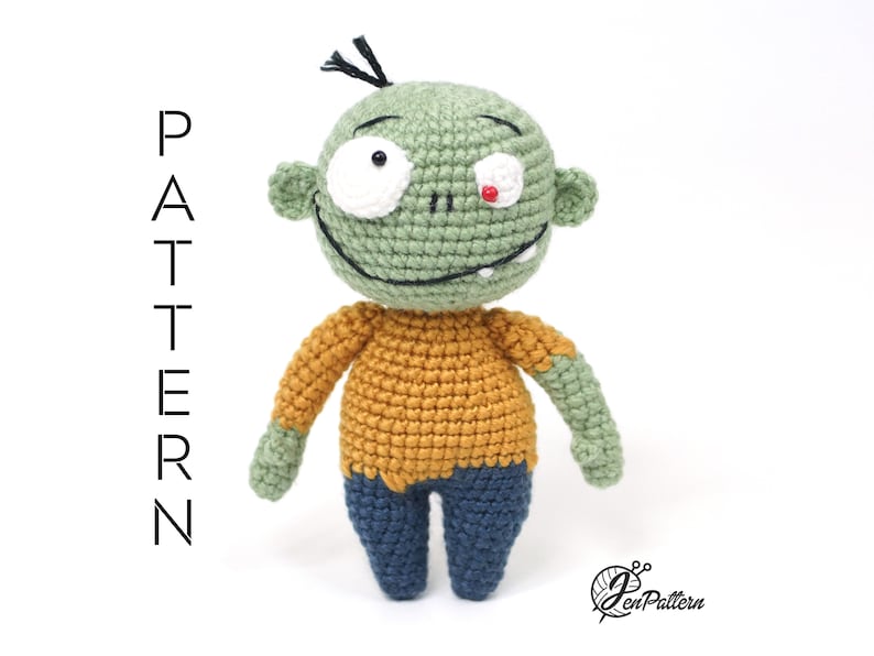 K&ouml;nnte beinhalten: Gr&uuml;ne geh&auml;kelte Zombie-Amigurumi-Puppe mit gelbem Shirt und blauer Hose. Die Puppe hat ein wei&szlig;es Auge und ein rotes Auge.