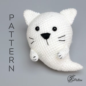 Könnte beinhalten: Eine weiße, gehäkelte, geisterförmige Katzenfigur mit schwarzen Perlenaugen, einer gestickten schwarzen Nase und Schnurrhaaren. Das Wort PATTERN ist links vertikal in Schwarz gedruckt, unten rechts befindet sich ein JenPattern-Logo.
