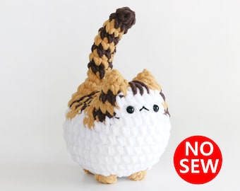 May include: A crocheted cat toy with brown, white, and orange yarn. The cat has a long tail and is standing on a white surface. The text "NO SEW" is visible in the image.