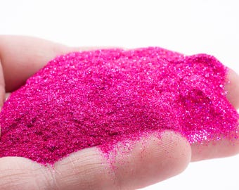 May include: A close-up of a hand holding a pile of bright pink glitter.