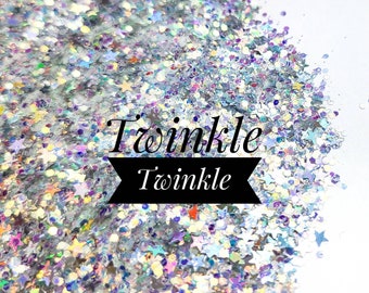May include: A close-up of iridescent glitter with a mix of silver and rainbow colors. The glitter is shaped like stars and is arranged in a pile. The text "Twinkle Twinkle" is written in black on a white background.