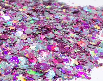 May include: A pile of iridescent glitter in shades of pink, purple, and silver. The glitter is made up of various shapes, including stars, hexagons, and circles.