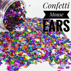 May include: A clear jar spills out colourful confetti shaped like mouse ears onto a white surface. The confetti is a mix of colours including purple, blue, green, gold, and red. The text "Confetti Mouse EARS" is displayed in black.