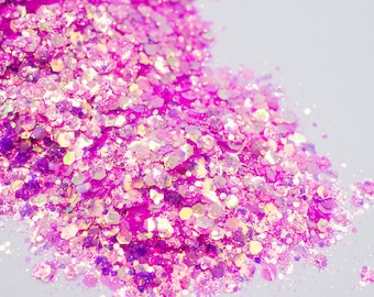 May include: Close-up of a pile of iridescent pink glitter. The glitter is composed of various sized hexagonal shapes, reflecting light with a shimmering effect. The overall color palette is a vibrant mix of pink and iridescent hues.