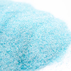 May include: A close-up of a pile of light blue glitter. The glitter is very fine and has a slight iridescent sheen.