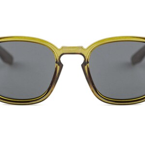 Op de afbeelding: Olijfgroene zonnebril met donkergrijze glazen. De monturen zijn vierkant met afgeronde randen en een sleutelgatbrug. De veren zijn donkerder bruin. De zonnebril heeft een klassieke, retro stijl.