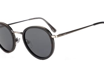 May include: Round black sunglasses with a silver metal frame. The sunglasses have dark lenses and a subtle wood grain detail on the frame.
