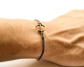 May include: A brown leather cord bracelet with a gold-toned anchor charm.
