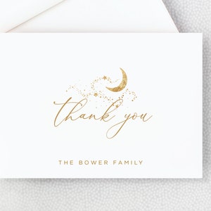 May include: A white thank you card with gold foil lettering that says "thank you" and a crescent moon with stars design. The bottom of the card says "The Bower Family".