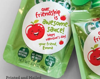 Può includere: Sacchetti verdi di salsa di mele con un'etichetta bianca circolare che recita "La nostra amicizia è una salsa fantastica! Buon San Valentino!" e una grafica di mela rossa sorridente. La busta è di 90 g.