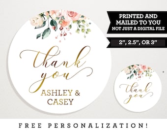 Op de afbeelding: Ronde bedank stickers met een bloemenontwerp in roze en groene tinten. De tekst "Bedankt" staat in gouden schrijfletter. De stickers zijn verkrijgbaar in de maten 2, 2,5 of 3 inch. De tekst "Ashley & Casey" staat onder de bedankboodschap.