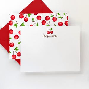 May include: White stationery with a red cherry design and the name "Chelsea Miller" printed in brown text.