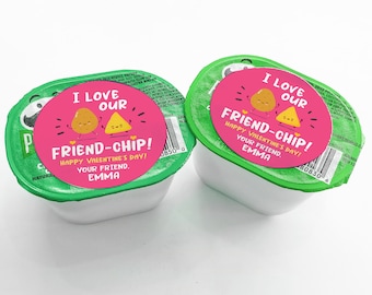 May include: Two individual containers of Pringles potato chips with green lids and white bases. Each container has a pink sticker that reads "I Love Our Friend-Chip! Happy Valentine's Day! Your Friend, Emma" with cartoon potato and chip illustrations.