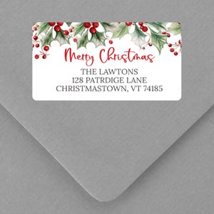 May include: A rectangular white label with a watercolor design of holly leaves and red berries. The label reads "Merry Christmas" in red script, followed by an address in black text.