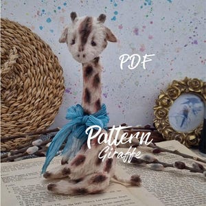 May include: A handmade stuffed giraffe with a long neck and brown spots, adorned with a blue ribbon. The text "Pattern Giraffe" and "PDF" are overlaid on the image. The giraffe is set on a vintage book.