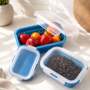 Puede incluir: Tres recipientes de almacenamiento de alimentos rectangulares azules con tapas transparentes de cierre. Un recipiente grande contiene pimientos rojos y naranjas, uno mediano contiene granos de café tostados y uno pequeño está vacío sin tapa.