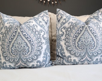 May include: Two decorative throw pillows with a white background and a blue and gray paisley pattern.