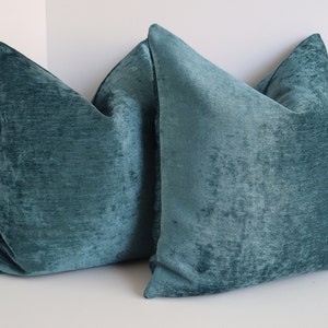 Puede incluir: Dos almohadas de terciopelo azul turquesa con superficie texturizada.