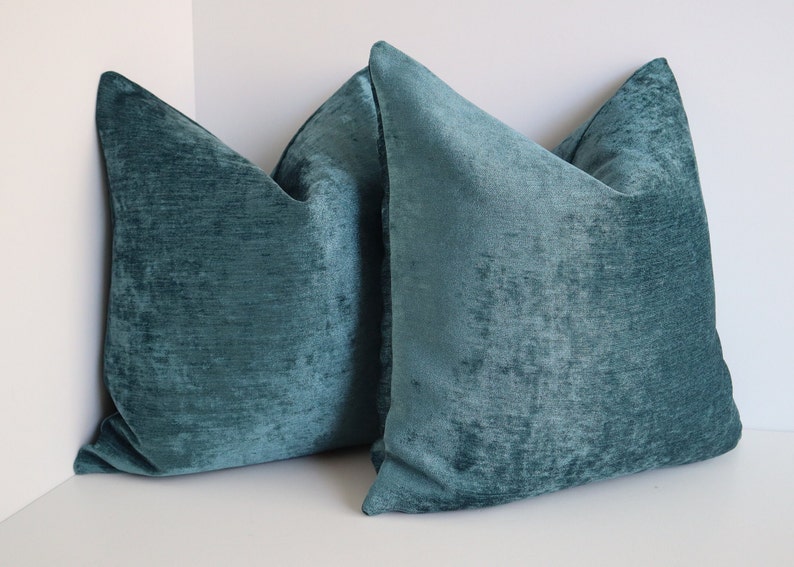 Puede incluir: Dos almohadas de terciopelo azul turquesa con superficie texturizada.