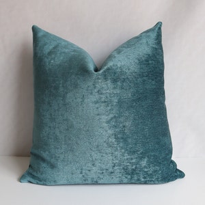 May include: Teal blue velvet throw pillow with a soft, textured surface.