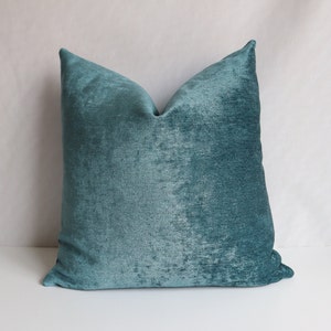 Puede incluir: Almohada de terciopelo azul turquesa con una superficie suave y texturizada. La almohada es de forma cuadrada y tiene un dise&ntilde;o sencillo.