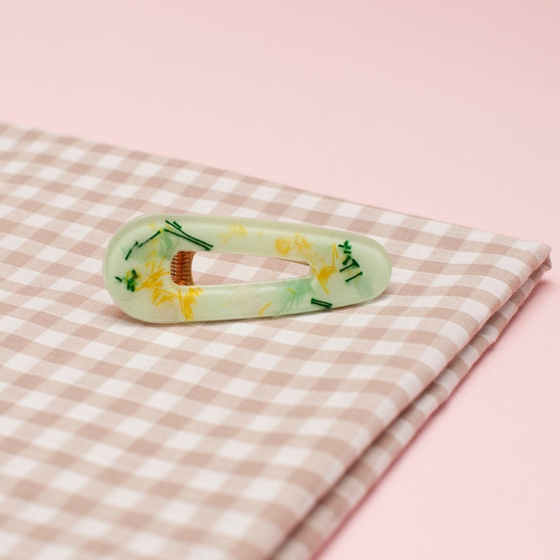 A green and yellow resin hair clip, filled with thread offcuts.