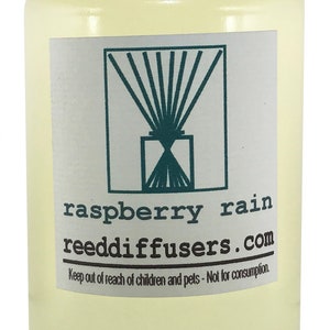 May include: A clear glass bottle with a white cap filled with a yellow liquid. The label reads "raspberry rain reeddiffusers.com Keep out of reach of children and pets - Not for consumption."