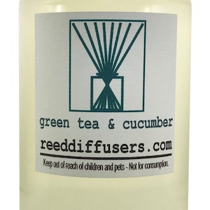 May include: A clear glass bottle with a white cap filled with a light yellow liquid. The label reads "green tea & cucumber reeddiffusers.com" and "Keep out of reach of children and pets - Not for consumption."