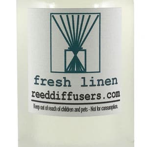 May include: A clear glass bottle with a white cap filled with a light yellow liquid. The label reads "fresh linen reeddiffusers.com" and includes a graphic of a diffuser with reeds. The text "Keep out of reach of children and pets - Not for consumption." is also on the label.