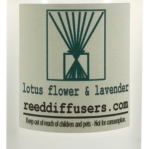 May include: A clear, frosted glass bottle with a white cap, containing a liquid. A label displays a green graphic and the text "lotus flower & lavender" and "reeddiffusers.com". The label also includes a warning.