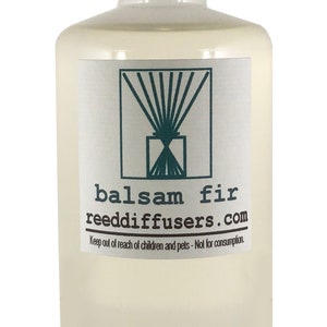 May include: A clear glass bottle with a white cap, filled with a light yellow liquid. The label reads "balsam fir reeddiffusers.com" and includes a stylized image of a reed diffuser. The label also includes the text "Keep out of reach of children and pets - Not for consumption."