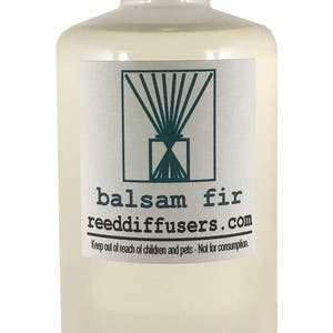 May include: A clear glass bottle with a white cap, filled with a light yellow liquid. The label reads "balsam fir reeddiffusers.com" and "Keep out of reach of children and pets - Not for consumption."