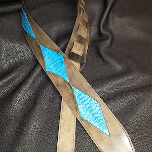 May include: A brown leather guitar strap with a blue diamond pattern. The strap has a distressed look and is made of high-quality leather.