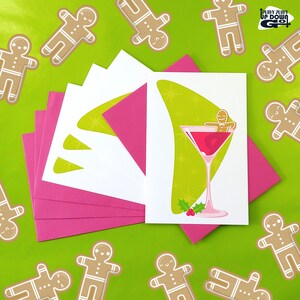 May include: A set of five pink and white greeting cards with a green and white illustration of a gingerbread person in a martini glass. The text on the card reads "Pushy Pushy Up Down Go".