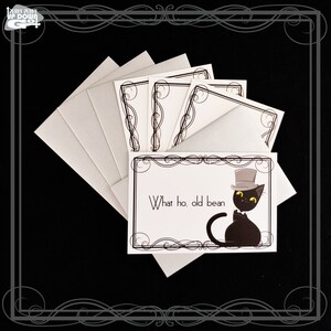 May include: A set of five blank greeting cards with black and white ornate borders. The card on top features a black cat wearing a top hat and bow tie with the text "What ho, old bean".