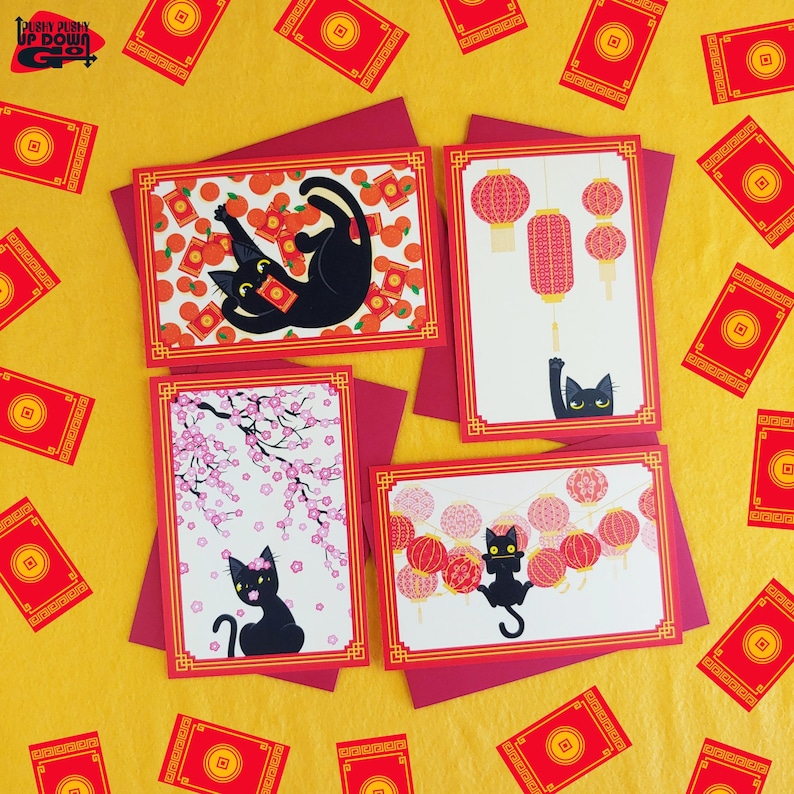 May include: Four greeting cards with red borders and envelopes, featuring black cats and Chinese New Year themes. Designs include cats with oranges, lanterns, and cherry blossoms. Red envelopes and cards with gold coins are scattered on a yellow background.