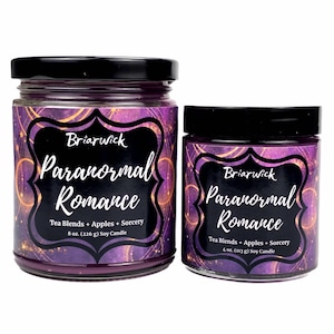 May include: Two glass soy candles with black lids, featuring purple and gold celestial labels. The larger candle is 8 oz. (226 g) and the smaller is 4 oz. (113 g). Both labels read Briarwick, Paranormal Romance, and Tea Blends + Apples + Sorcery.