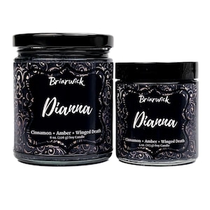 May include: Two glass jars of soy candles with black lids. The labels read "Briarwick Dianna" with "Cinnamon + Amber + Winged Death" and the weight of the candle. The jars have a black background with a decorative pattern.