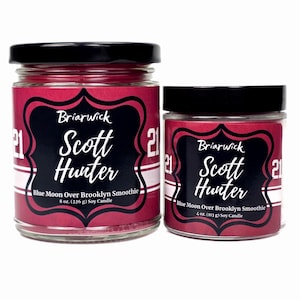 May include: Two glass jars of soy candles with black lids. The labels are red with a black decorative frame and white text that reads "Briarwick Scott Hunter". The text "Blue Moon Over Brooklyn Smoothie" is also on the label. One candle is 8 oz (226 g), the other is 4 oz (113 g).